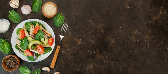 A healthy salad of chicken breast, fresh vegetables, spinach leaves, avocado and tomatoes on a dark background. Salad of greens with meat. The concept of diet food. Copy space. Benner food.