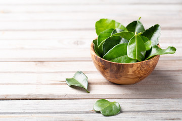 Kaffir lime Leaves in a wooden bowl on light table