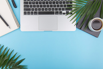 Top view of office desk on blue background.Laptop,notebook,phone,coffee cup 