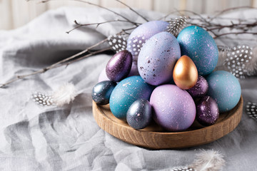 Easter. Festive bright eggs in a wooden bowl on a background of gray cotton fabric.