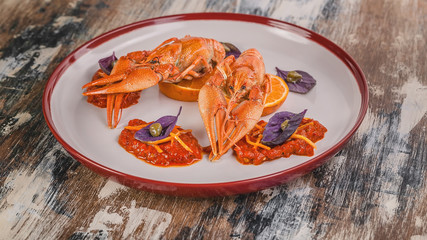 Food banner. Boiled crayfish. Delicacy with chili pepper sauce, orange, zest, basil and capers on a plate. Haute cuisine