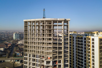 Aerial view of concrete frame of tall apartment building under construction in a city.