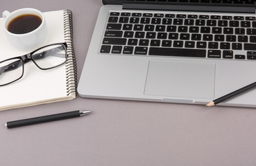Top view of office desk on gray background.Laptop,notebook,phone,coffee cup