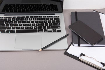 Top view of office desk on gray background.Laptop,notebook,phone,coffee cup