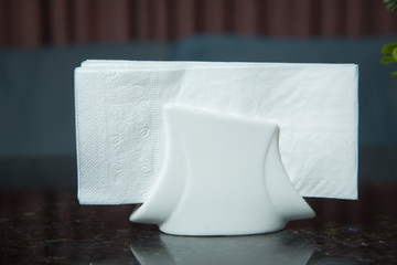 White napkins in a metal napkin holder, spices salt and pepper on a woodeglass table, panoramic view. toothpick . A table in a cafe or restaurant.