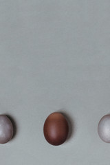 Large brown egg between small gray. Easter minimalistic concept, vertical, place for you text