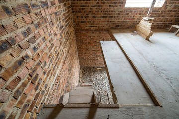 Interior of unfinished brick house with concrete floor and bare walls ready for plastering under construction. Real estate development