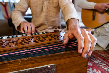 Front angle view of senior male shamanic playing indian musical instrument harmonium as sacred and kirtan music for peaceful yogic power 