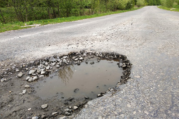 Close up of big pothole with dirty rain water of the road.