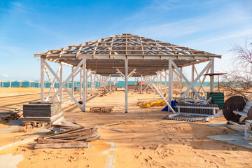 Unfinished wooden structure for canopy in the tourist resort on beach by the sea in off-season