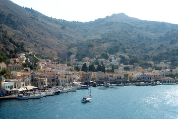 The harbour on the beautiful Greek island of Symi.  Neo classical houses are seen on both sides of the bay, on the steep hillsides.