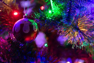 Obraz na płótnie Canvas A close up photograph of a Christmas pudding bauble hanging from a green Christmas tree surrounded with multicoloured fairy lights