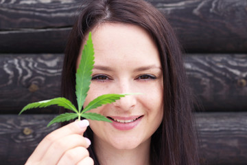 Beautiful girl with hemp leaves near the face. Woman with hemp.