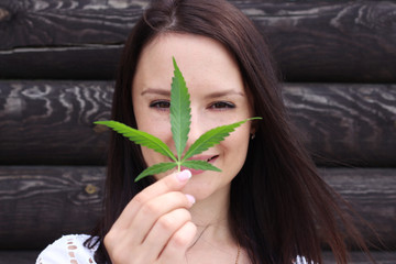 Beautiful girl with hemp leaves near the face. Woman with hemp.