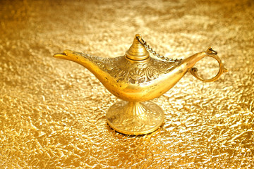 Lamp of wishes - Aladdin lamp on a golden background. The concept of wealth and fulfillment of...