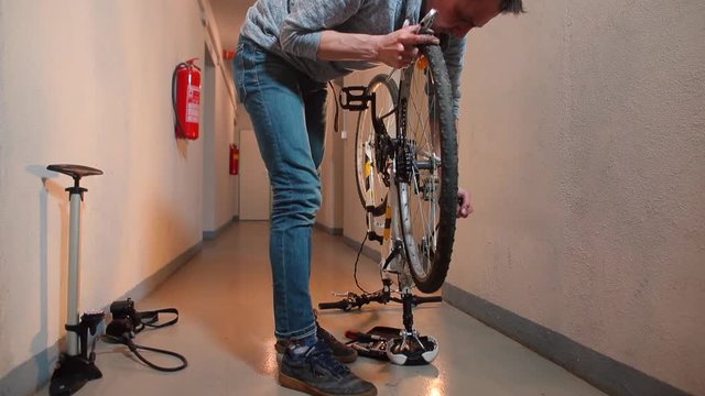 A man is repairing a bicycle wheel in a garage. 