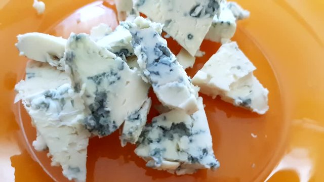 Pieces of dorblu cheese on an orange plate, close-up