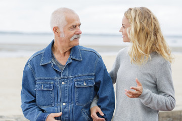 father and daughter arm in arm walking by the beach