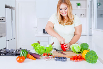 Blonde overweight woman preparing fresh vegetable