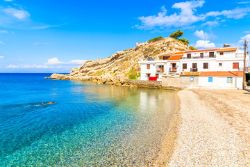 Snorkeler swimming in crystal clear azure sea water in Kokkari village with typical white houses on...