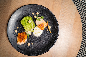 Top view Cezar salad deconstructed , grilled chicken, sauce and salad on black plate 