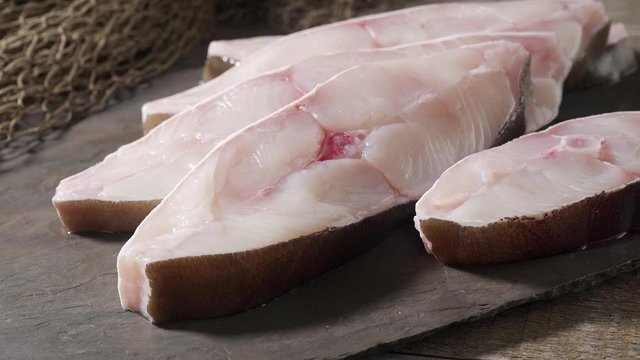 Fresh halibut steaks on slate with commercial fishing net.