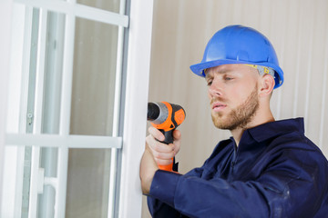 construction worker using drill to install window