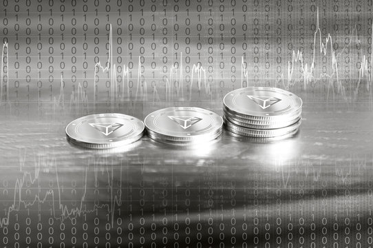 Tronix (TRX) digital crypto currency. Stack of silver coins against the background of numbers and stock quotes. Cyber money.