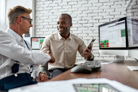 Move Forward. Successful Businessmen Trading Stocks. Stock Traders Looking At Graphs, Indexes And Numbers On Multiple Computer Screens. Two Colleagues In Modern Office