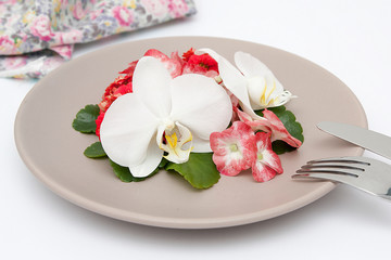 Plate with flowers and cutlery on a white table. Diet concept