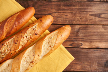 Three crispy french baguettes lie on an old wooden table with free space for text