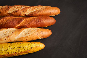 Three crispy french baguettes lie on an old wooden table with free space for text