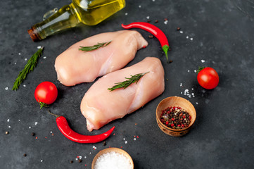 Raw chicken fillet , tomatoes and rosemary , sunflower oil on a stone background
