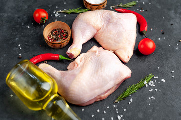 chicken legs with spices, tomatoes, sunflower oil on a stone background.
