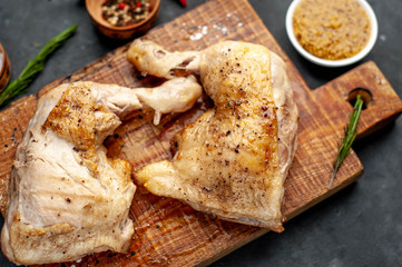grilled chicken legs, ready to eat with spices, served on a cutting board on a stone background