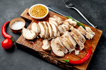grilled chicken fillet with spices, tomatoes, mustard on a stone background