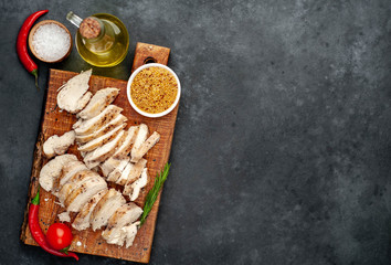 grilled chicken fillet with spices, tomatoes, mustard on a stone background