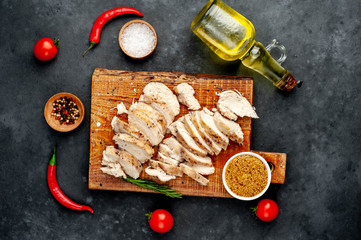 grilled chicken fillet with spices, tomatoes, mustard on a stone background