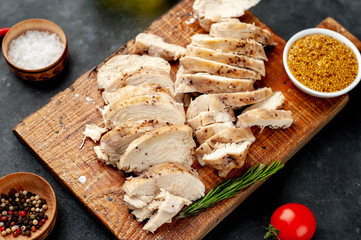 grilled chicken fillet with spices, tomatoes, mustard on a stone background