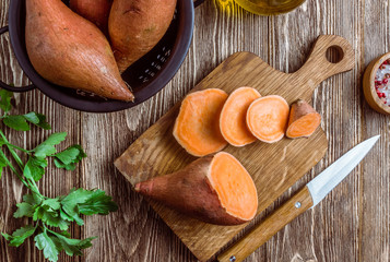 Organic farm sweet potato on rustic wooden background. Healthy eating and zero waste concept. Top...
