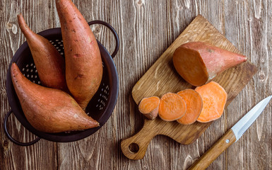 Organic farm sweet potato on rustic wooden background. Healthy eating and zero waste concept. Top...