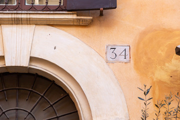 number 34, ancient house number plate on brick wall, Italy