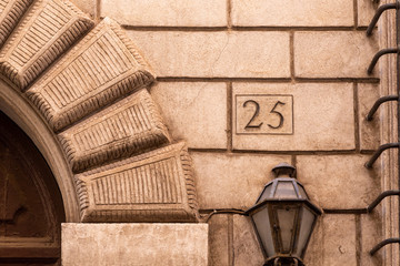 number 25 ancient house number plate on brick wall, Italy