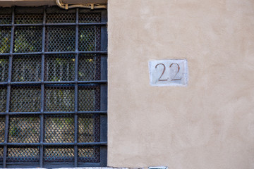 number 22, ancient house number plate on brick wall, Italy