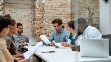 Teamwork and collaboration. Group of young business people discussing something while working...