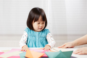 toddler girl learn making  Origami at home against white background