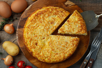 Spanish omelette with potatoes and onion, typical Spanish cuisine. Tortilla espanola. Rustic dark background. Top view