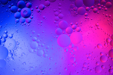 Oil drops on water surface color abstract background. blue and pink circles