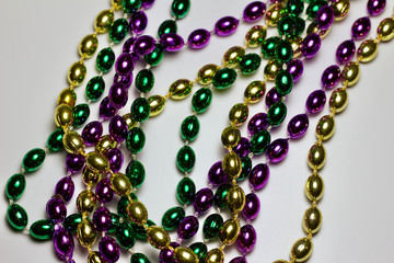 Close up view of traditional colorful Mardi Gras bead necklaces on white background with copy space