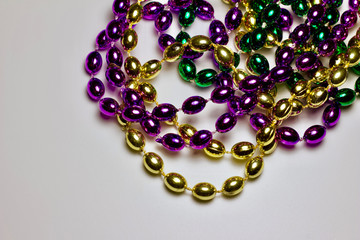 Close up view of traditional colorful Mardi Gras bead necklaces on white background with copy space